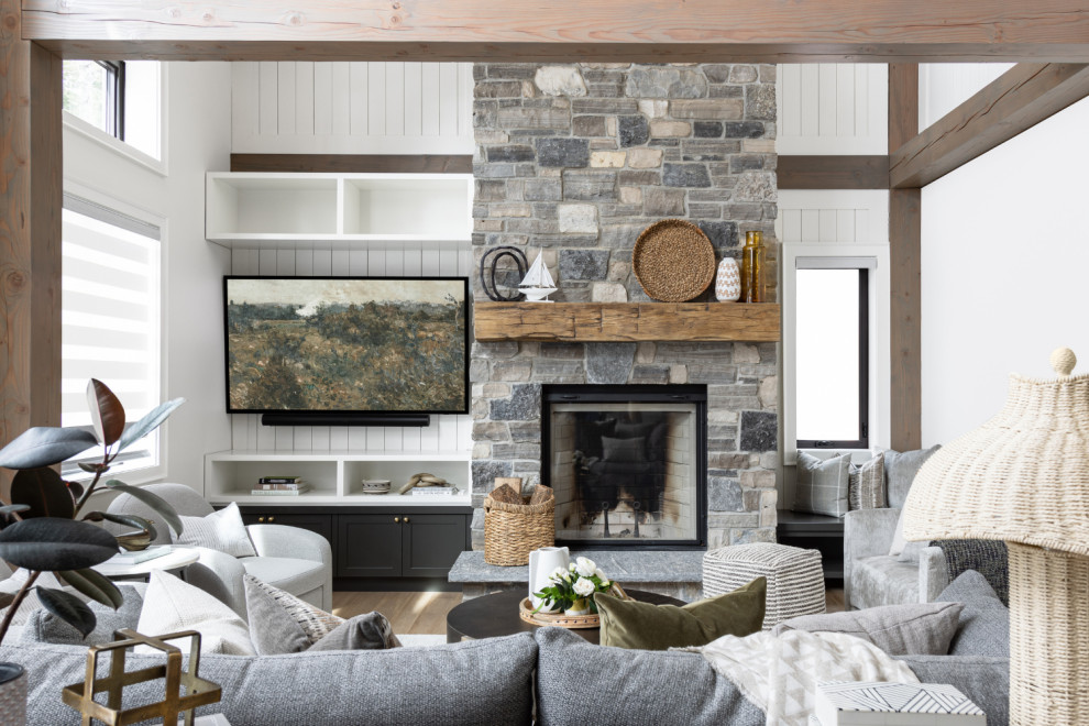 This is an example of a large transitional open concept living room in Toronto with white walls, a standard fireplace, a stone fireplace surround, panelled walls and a built-in media wall.