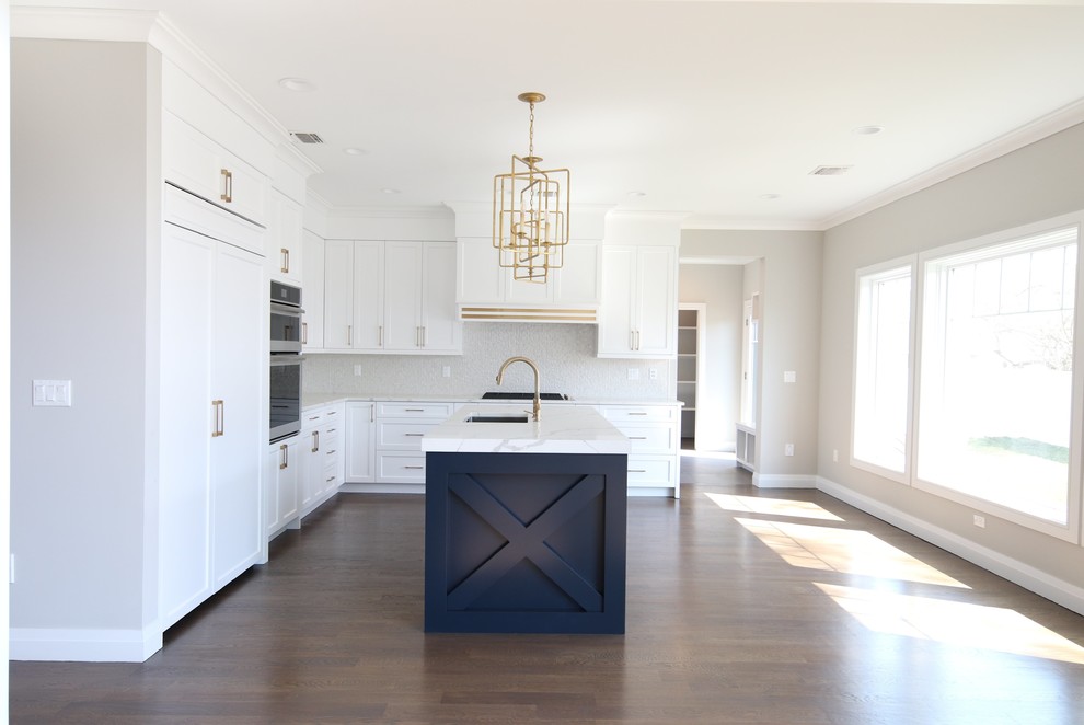 Inspiration for a transitional medium tone wood floor kitchen remodel in New York with an undermount sink, white cabinets, quartz countertops, white backsplash, porcelain backsplash, paneled appliances, an island and white countertops