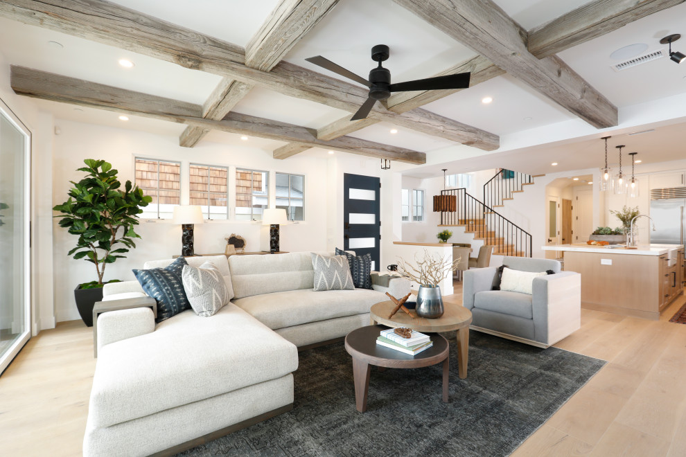 Photo of a beach style open concept living room in Orange County with white walls, light hardwood floors and exposed beam.