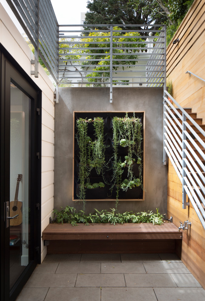 This is an example of an eclectic courtyard patio in San Francisco with a vertical garden and natural stone pavers.