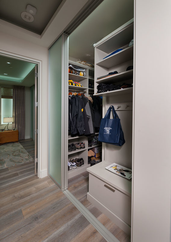 This is an example of a small contemporary gender-neutral built-in wardrobe in Other with light hardwood floors, flat-panel cabinets and beige floor.