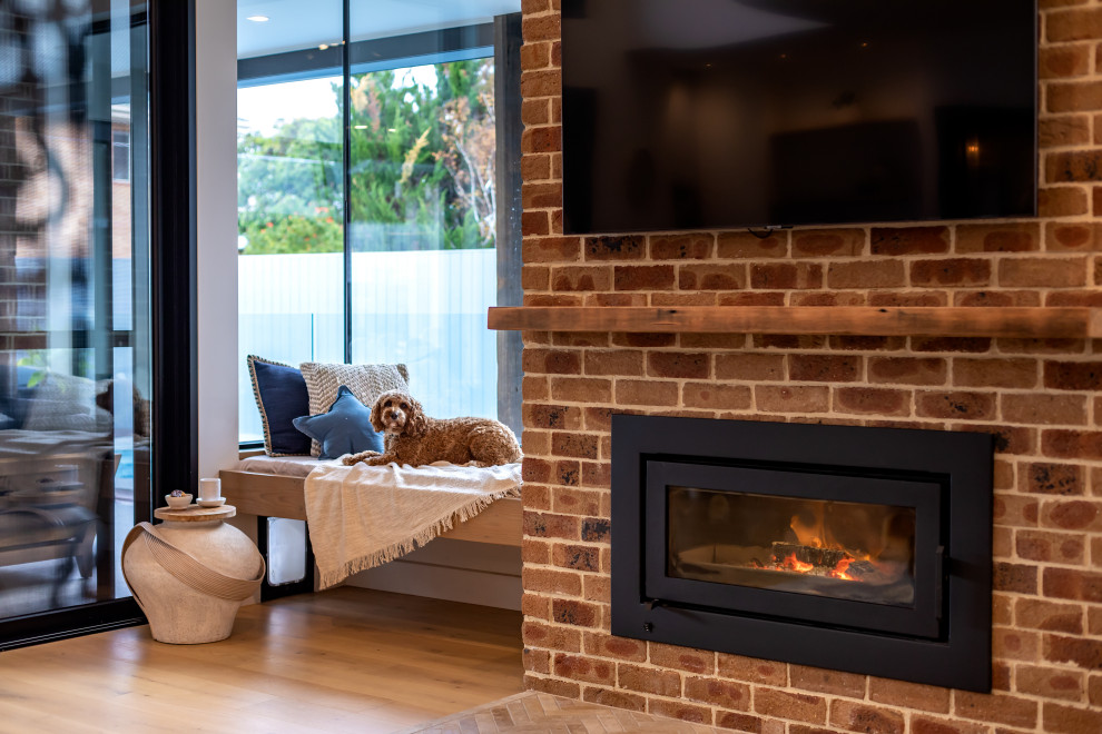 Photo of a large open plan living room in Adelaide with white walls, light hardwood flooring, a ribbon fireplace, a brick fireplace surround, a wall mounted tv, brown floors and brick walls.