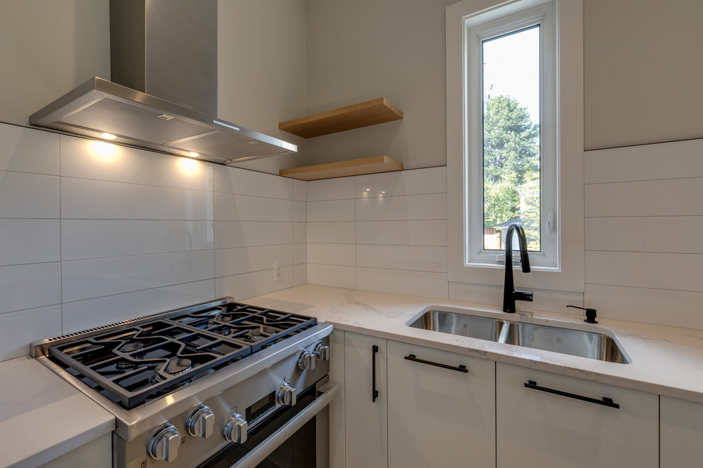 Mid-sized contemporary single-wall eat-in kitchen in Vancouver with flat-panel cabinets, white cabinets, quartzite benchtops, grey splashback, marble splashback, stainless steel appliances, light hardwood floors, beige floor, white benchtop, an undermount sink and with island.