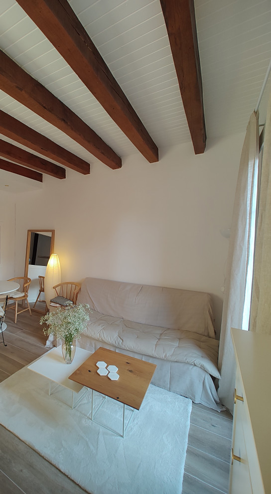 This is an example of a small scandi mezzanine games room in Barcelona with white walls, ceramic flooring, a freestanding tv, brown floors, exposed beams and brick walls.