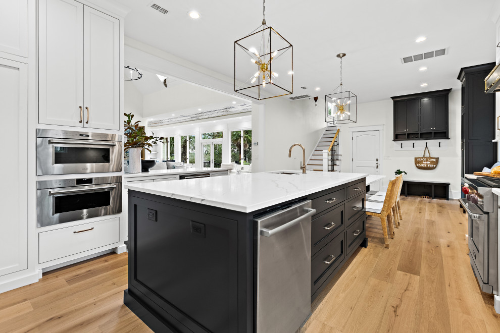 Kitchen - large transitional u-shaped light wood floor kitchen idea with an undermount sink, shaker cabinets, white cabinets, quartz countertops, white backsplash, marble backsplash, paneled appliances, two islands and white countertops