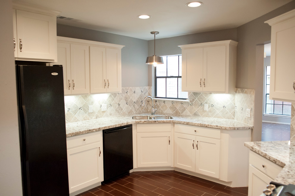 Inspiration for a mid-sized transitional u-shaped separate kitchen in Houston with an undermount sink, recessed-panel cabinets, white cabinets, granite benchtops, grey splashback, stone tile splashback, black appliances and porcelain floors.