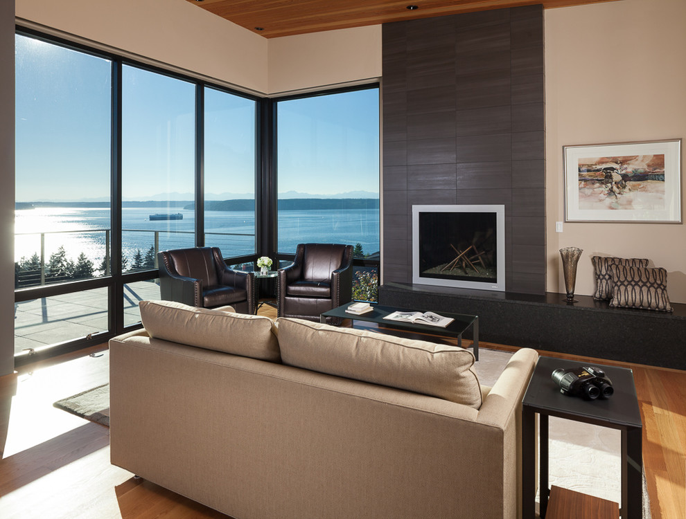 Mid-sized contemporary formal open concept living room in Seattle with beige walls, medium hardwood floors, a standard fireplace, a tile fireplace surround, no tv and brown floor.