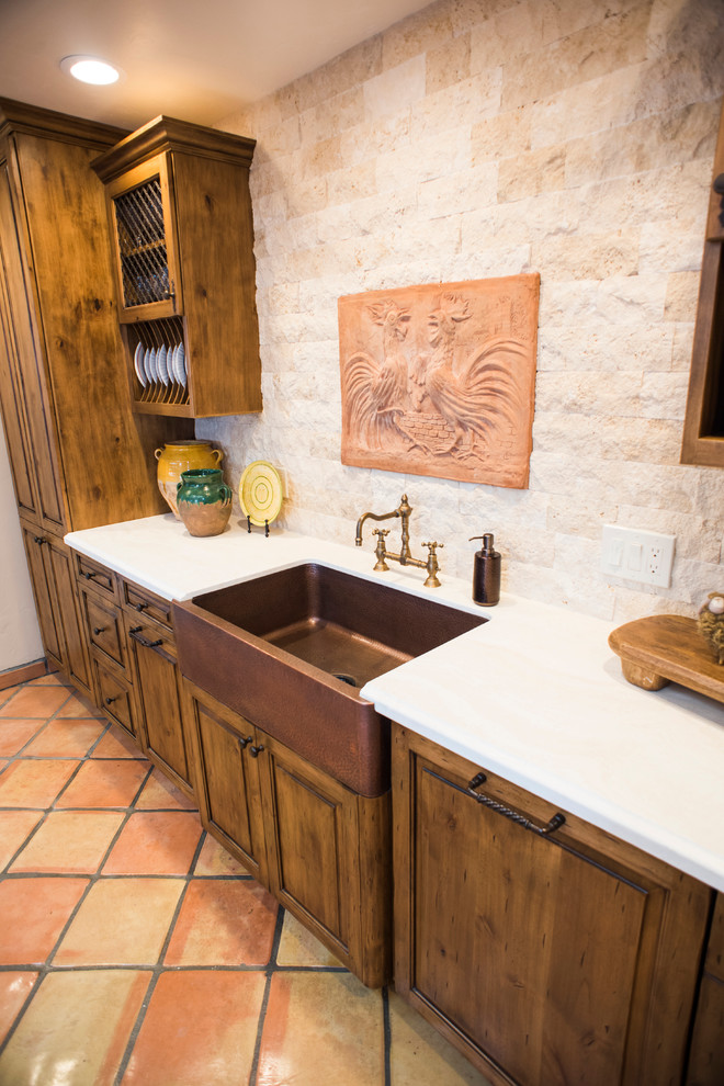 Inspiration for a mid-sized country eat-in kitchen in Phoenix with a farmhouse sink, raised-panel cabinets, medium wood cabinets, marble benchtops, white splashback, stone tile splashback, stainless steel appliances, terra-cotta floors and with island.