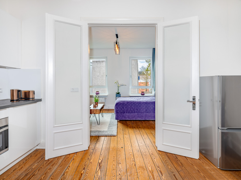 Immagine di un piccolo soggiorno mediterraneo chiuso con pareti bianche, pavimento in legno verniciato e carta da parati
