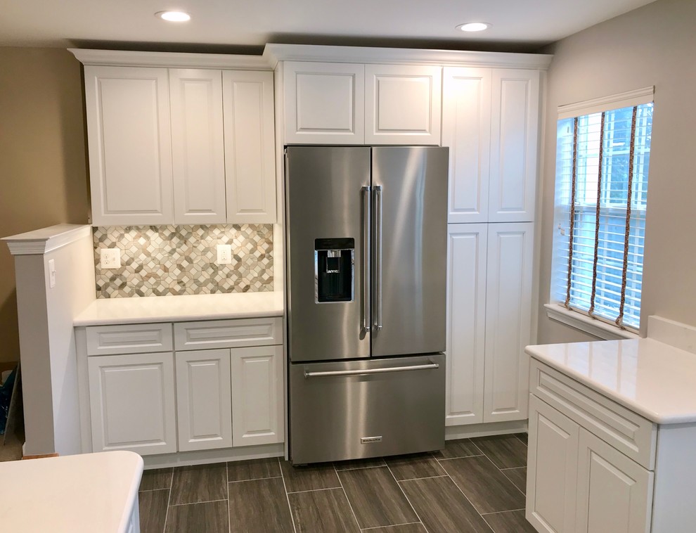 Design ideas for a mid-sized traditional l-shaped kitchen in DC Metro with a single-bowl sink, raised-panel cabinets, white cabinets, quartz benchtops, grey splashback, marble splashback, stainless steel appliances, ceramic floors, a peninsula, grey floor and white benchtop.