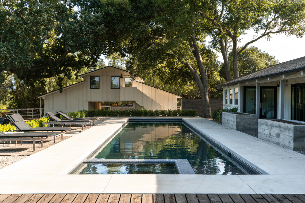 На фото: спортивный, прямоугольный бассейн на заднем дворе в стиле кантри с джакузи, домиком у бассейна и покрытием из бетонных плит с