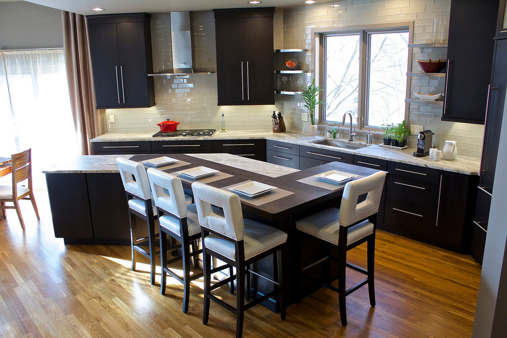 Mid-sized contemporary single-wall eat-in kitchen in Cincinnati with flat-panel cabinets, black cabinets, granite benchtops, with island, white splashback, subway tile splashback, an undermount sink, panelled appliances and dark hardwood floors.