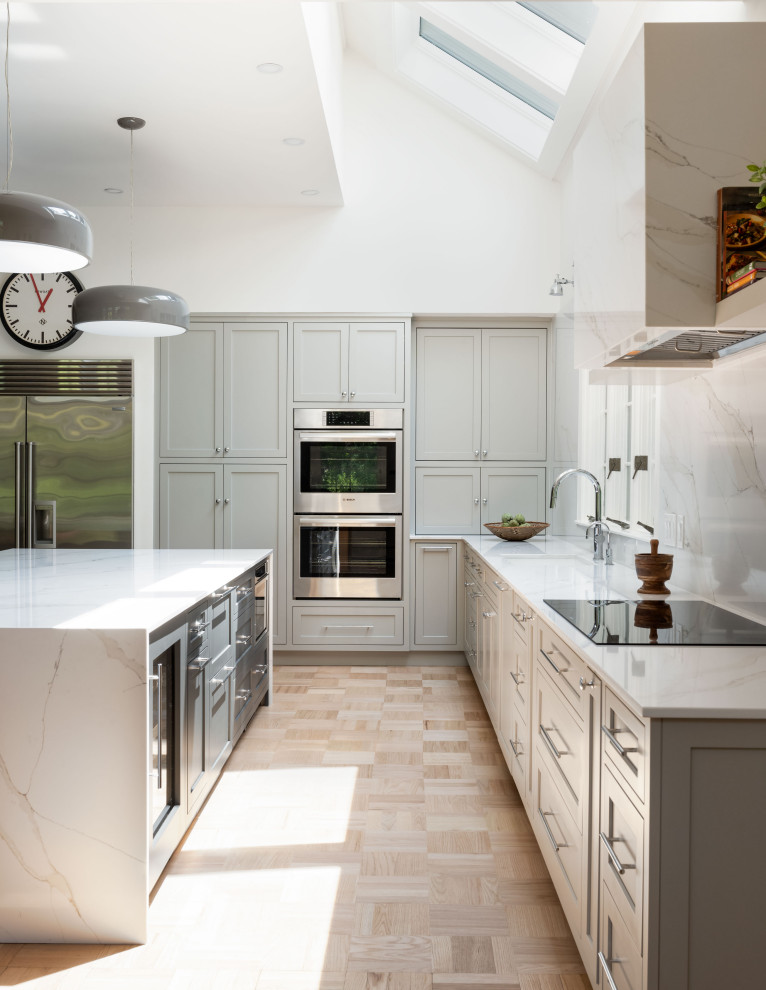 Large transitional light wood floor eat-in kitchen photo with an undermount sink, recessed-panel cabinets, gray cabinets, quartz countertops, white backsplash, quartz backsplash, stainless steel appliances, an island and white countertops