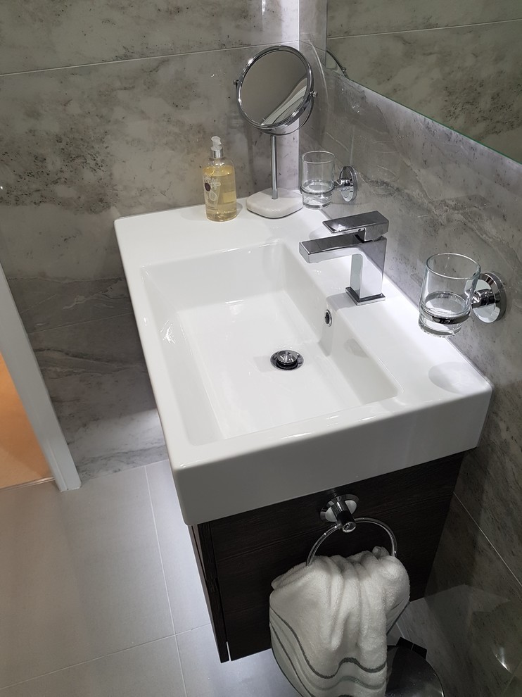 Inspiration for a medium sized contemporary ensuite bathroom in Other with flat-panel cabinets, dark wood cabinets, a corner shower, a wall mounted toilet, grey tiles, porcelain tiles, grey walls, porcelain flooring, a wall-mounted sink, grey floors and a hinged door.