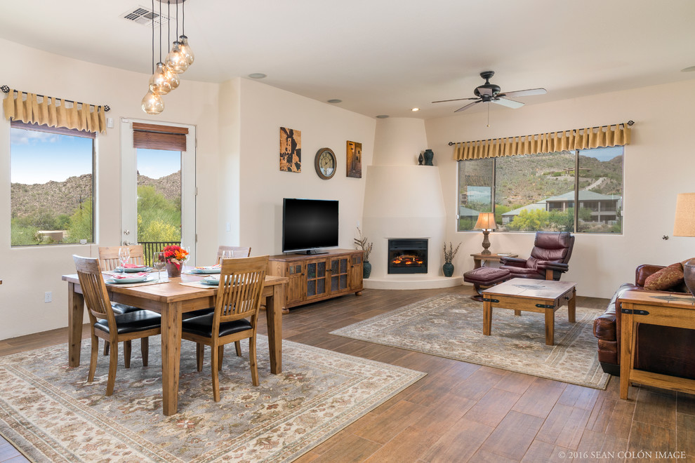 This is an example of a mid-sized traditional open concept living room in Phoenix with beige walls, medium hardwood floors, a corner fireplace, a plaster fireplace surround and a freestanding tv.