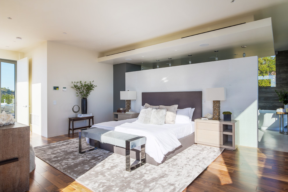 Large contemporary master bedroom in Los Angeles with white walls, medium hardwood floors and no fireplace.