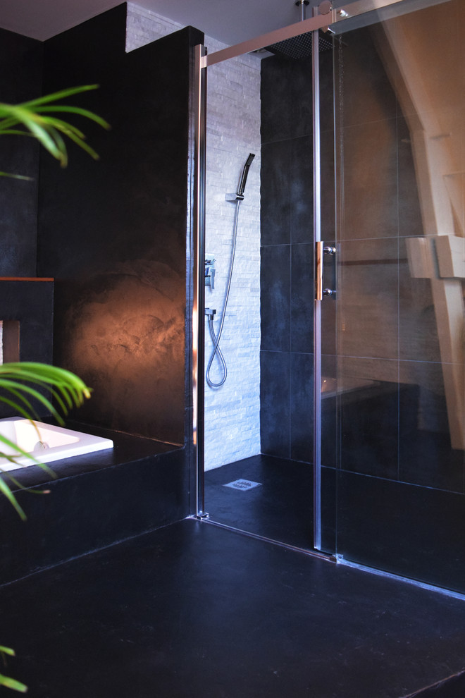 Design ideas for a mid-sized contemporary 3/4 bathroom in Paris with a curbless shower, black tile, stone tile, black walls, black floor and a sliding shower screen.