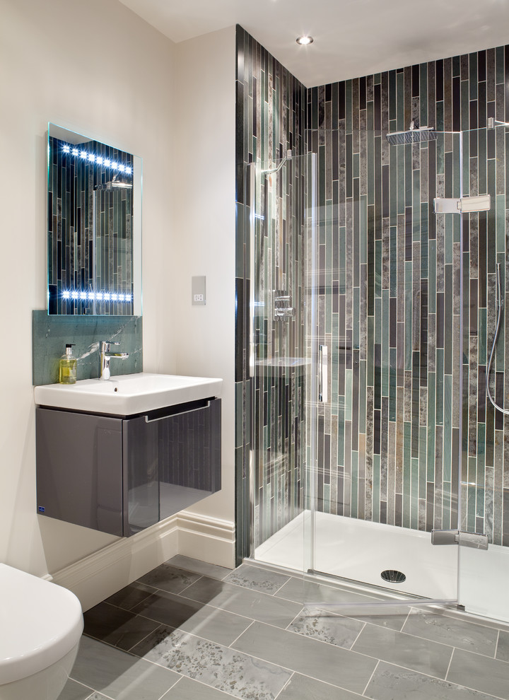 Design ideas for a contemporary 3/4 bathroom in London with flat-panel cabinets, grey cabinets, an alcove shower, gray tile, white walls, glass tile and a wall-mount sink.