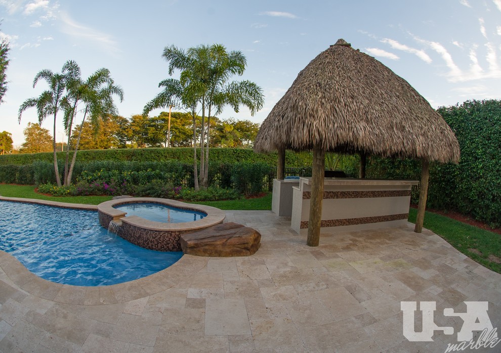 Photo of a large mediterranean backyard kidney-shaped aboveground pool in Miami with a water feature and natural stone pavers.