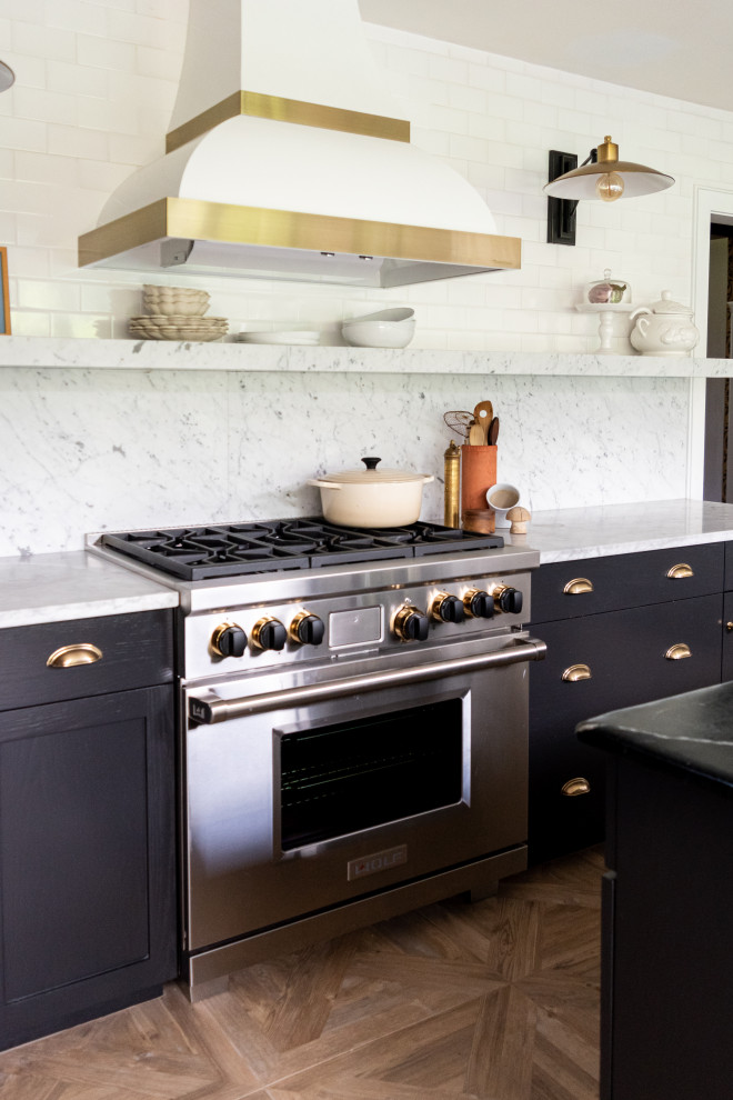 This is an example of a mid-sized modern u-shaped eat-in kitchen in Philadelphia with a triple-bowl sink, flat-panel cabinets, black cabinets, marble benchtops, white splashback, marble splashback, stainless steel appliances, ceramic floors, with island, beige floor and white benchtop.