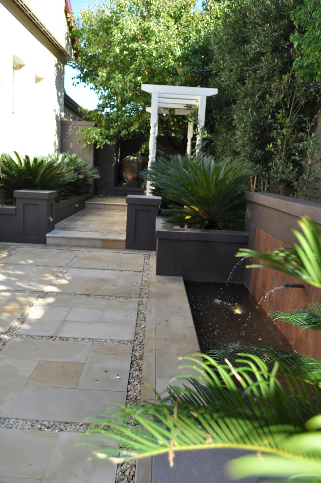 Design ideas for a small traditional side yard full sun formal garden in Perth with a retaining wall and natural stone pavers.
