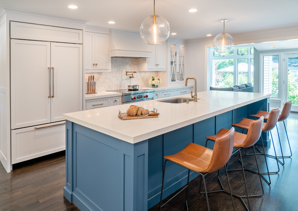 Photo of a beach style kitchen in Boston with white cabinets, white splashback, marble splashback, panelled appliances, with island, brown floor, white benchtop, an undermount sink, shaker cabinets and dark hardwood floors.