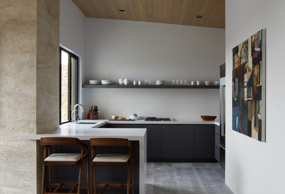 Cette photo montre une petite cuisine moderne en U et bois foncé avec un placard à porte plane, une crédence blanche, un électroménager en acier inoxydable, un sol en calcaire, îlot, un sol gris, un plan de travail blanc et un plafond en bois.