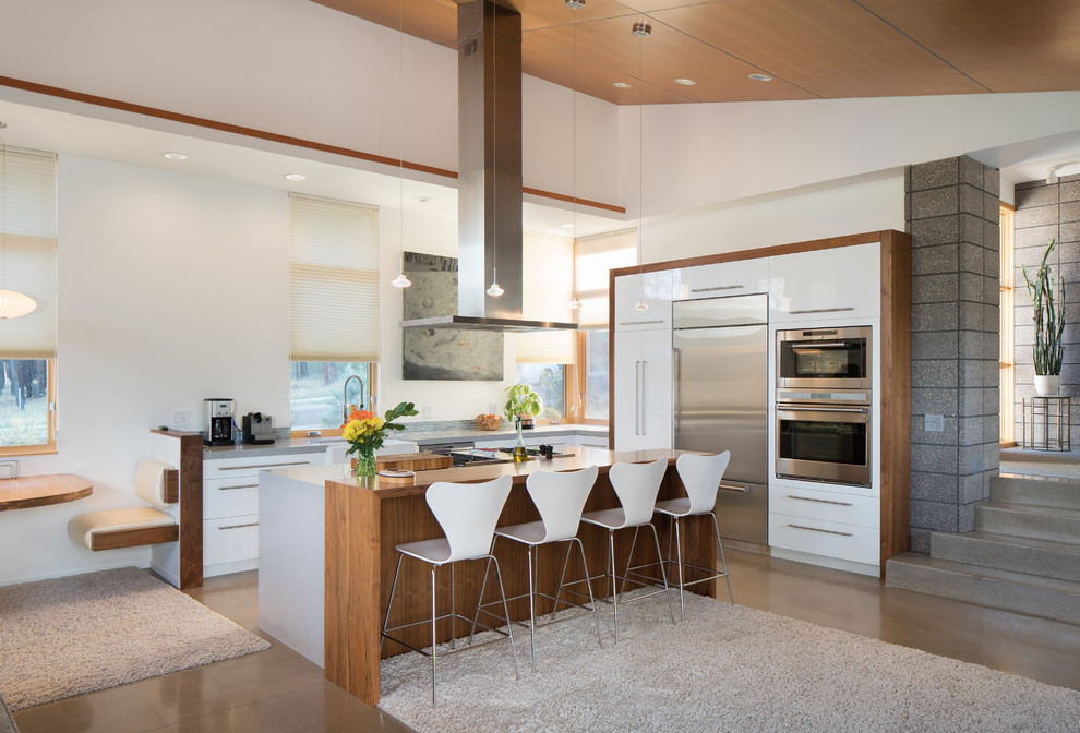 Design ideas for a mid-sized contemporary l-shaped open plan kitchen in Phoenix with flat-panel cabinets, white cabinets, quartzite benchtops, grey splashback, stainless steel appliances, concrete floors and with island.