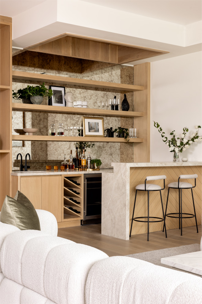 Example of a light wood floor and beige floor seated home bar design in Los Angeles with an integrated sink, flat-panel cabinets, beige cabinets, quartzite countertops, beige backsplash and beige countertops