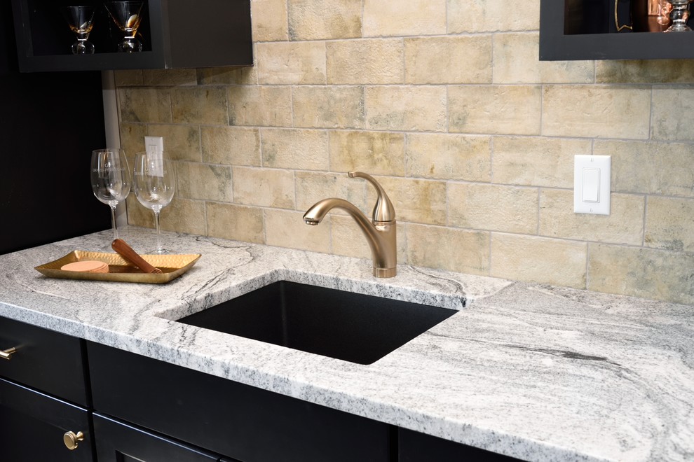 This is an example of a country galley wet bar in Milwaukee with recessed-panel cabinets, black cabinets, granite benchtops, beige splashback, ceramic splashback, grey benchtop and an undermount sink.