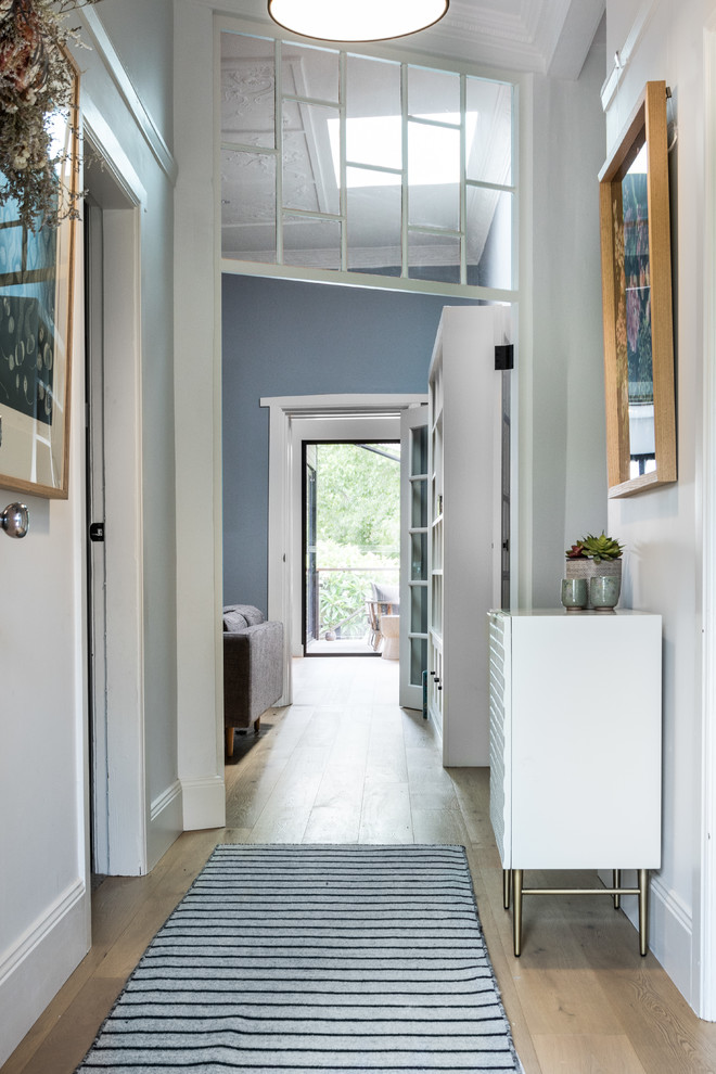Contemporary hallway in Sydney with white walls and light hardwood floors.