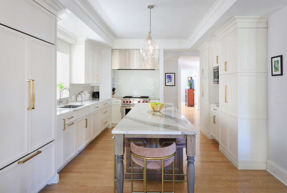Example of a large transitional u-shaped light wood floor and tray ceiling eat-in kitchen design in Chicago with a single-bowl sink, flat-panel cabinets, white cabinets, quartz countertops, white backsplash, glass tile backsplash, paneled appliances, an island and white countertops
