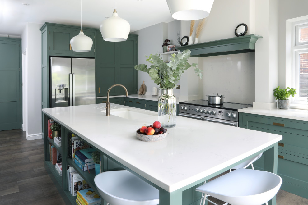 Photo of a mid-sized transitional separate kitchen in Essex with an undermount sink, shaker cabinets, green cabinets, quartzite benchtops, white splashback, engineered quartz splashback, stainless steel appliances, vinyl floors, with island, brown floor and white benchtop.