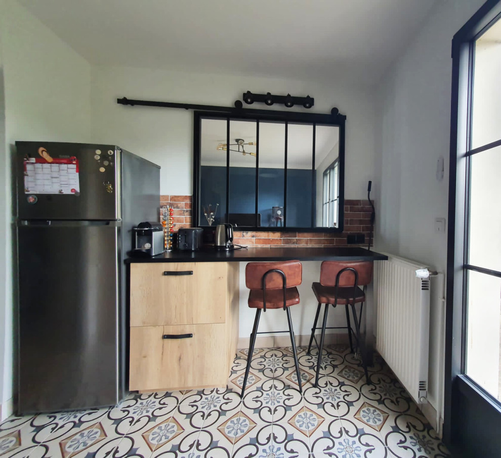 Imagen de cocina urbana de tamaño medio cerrada con puertas de armario negras, encimera de laminado, salpicadero de azulejos en listel y suelo de azulejos de cemento