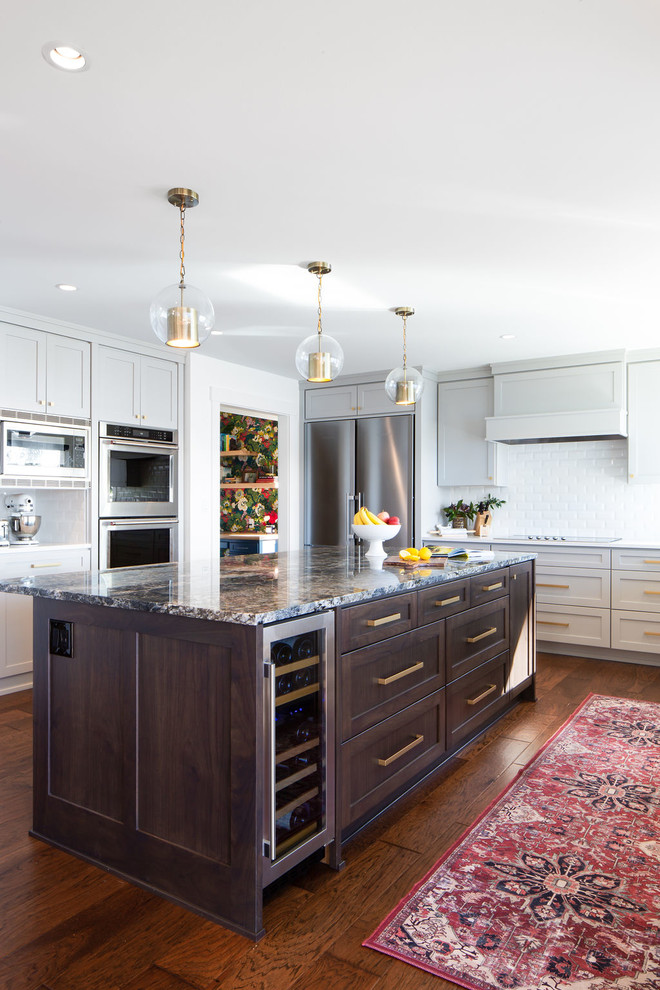 Inspiration for a large transitional l-shaped eat-in kitchen in Seattle with shaker cabinets, grey cabinets, white splashback, stainless steel appliances, dark hardwood floors, with island, brown floor, grey benchtop, granite benchtops and subway tile splashback.