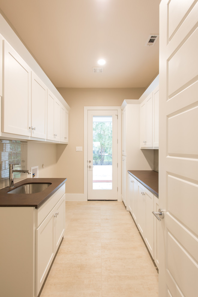 Design ideas for a large transitional galley dedicated laundry room in Dallas with an integrated sink, shaker cabinets, white cabinets, beige walls, porcelain floors and a side-by-side washer and dryer.
