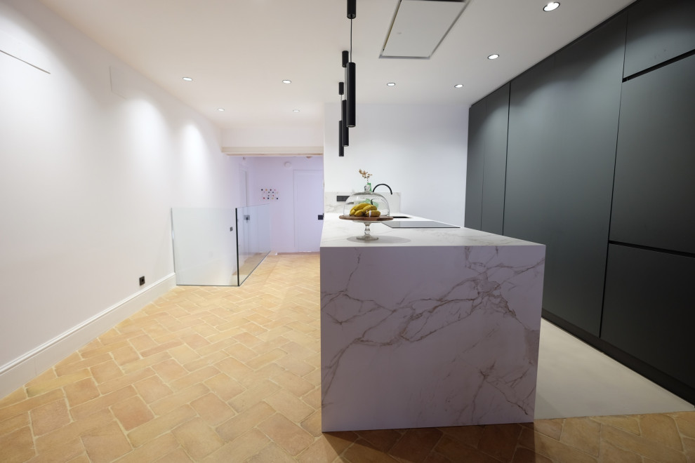 Large modern single-wall kitchen in Barcelona with an undermount sink, flat-panel cabinets, grey cabinets, quartz benchtops, white splashback, porcelain splashback, panelled appliances, terra-cotta floors, a peninsula, beige floor, white benchtop and recessed.