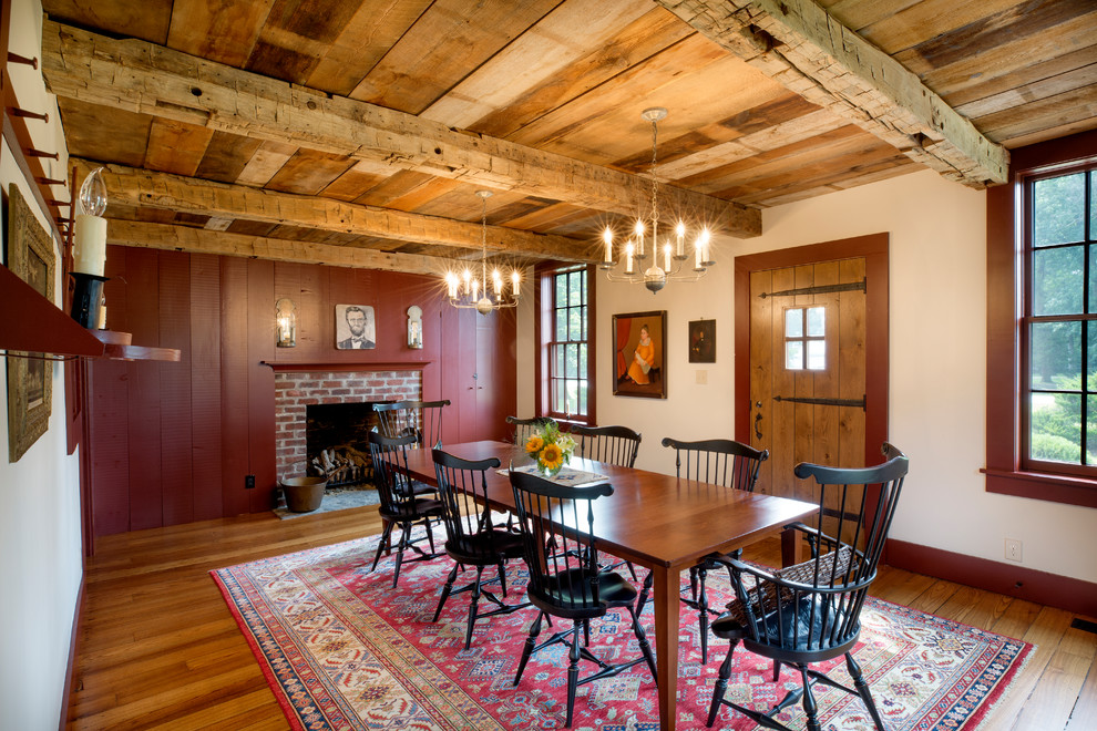 Design ideas for a country separate dining room in Columbus with red walls, medium hardwood floors, a standard fireplace and a brick fireplace surround.