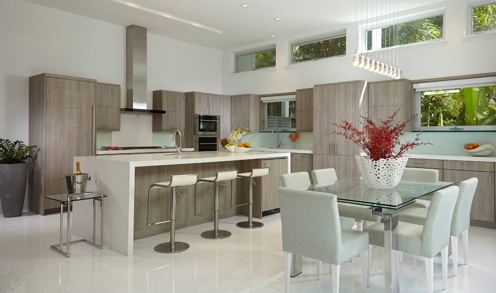 This is an example of a large contemporary galley open plan kitchen in Miami with a drop-in sink, flat-panel cabinets, grey cabinets, quartz benchtops, green splashback, glass sheet splashback, stainless steel appliances, marble floors and with island.