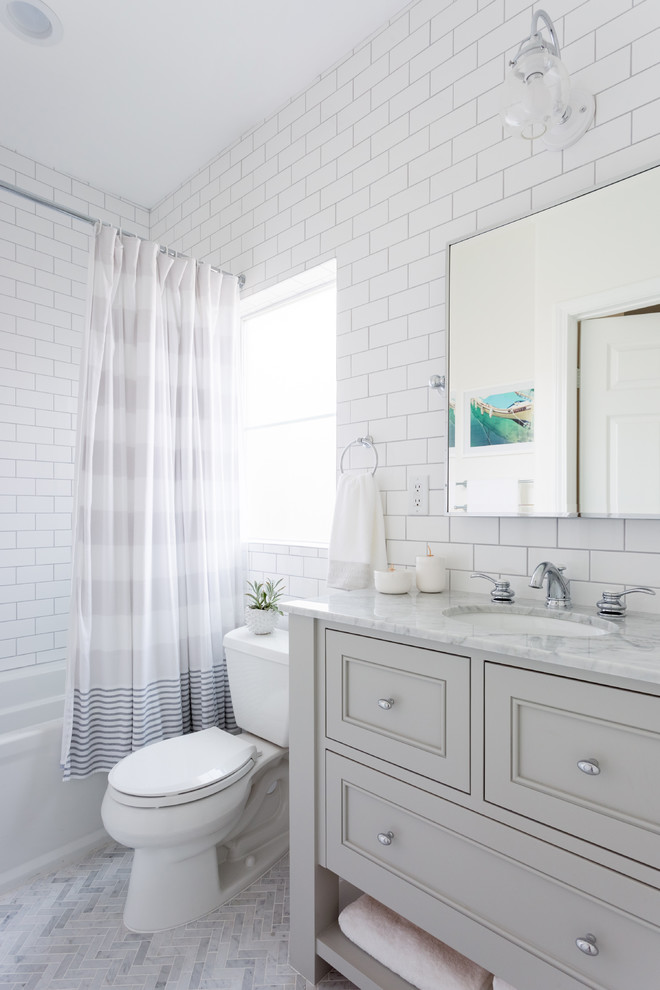 Mid-sized transitional kids bathroom in Los Angeles with recessed-panel cabinets, grey cabinets, white tile, subway tile, white walls, marble floors, marble benchtops, grey floor, an alcove tub, a shower/bathtub combo, a two-piece toilet, an undermount sink and a shower curtain.