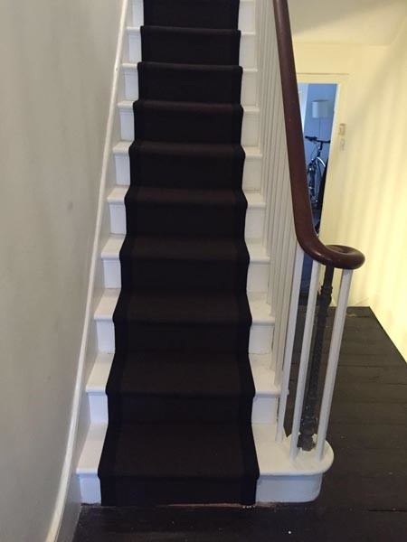 Design ideas for a mid-sized contemporary carpeted u-shaped staircase in London with wood railing.