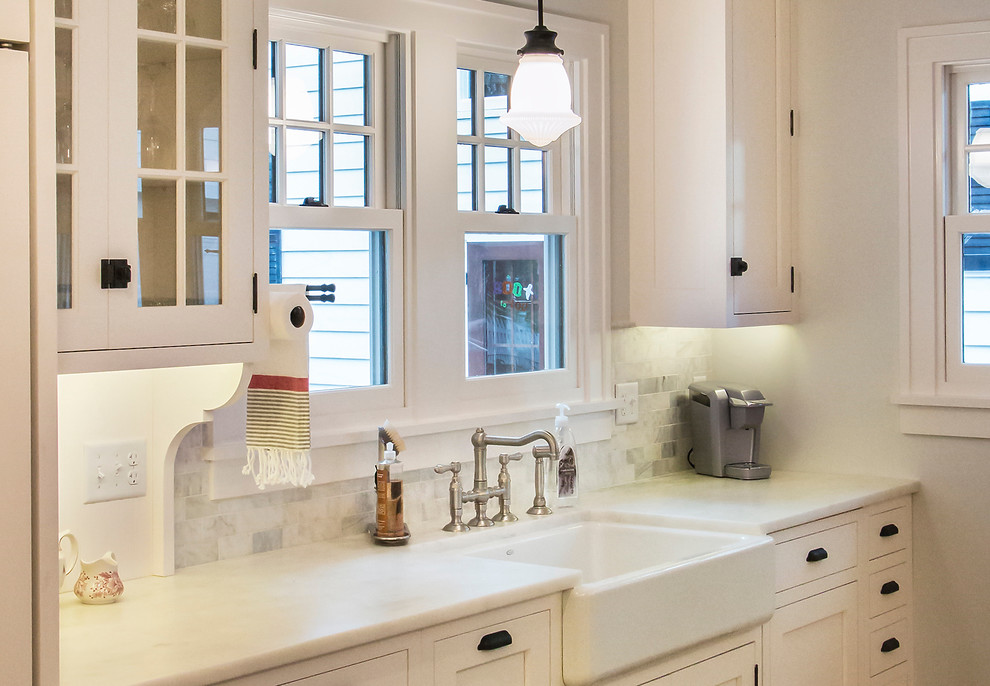 This is an example of a large traditional l-shaped eat-in kitchen in Chicago with a farmhouse sink, flat-panel cabinets, white cabinets, marble benchtops, white splashback, stone tile splashback, panelled appliances, medium hardwood floors and with island.