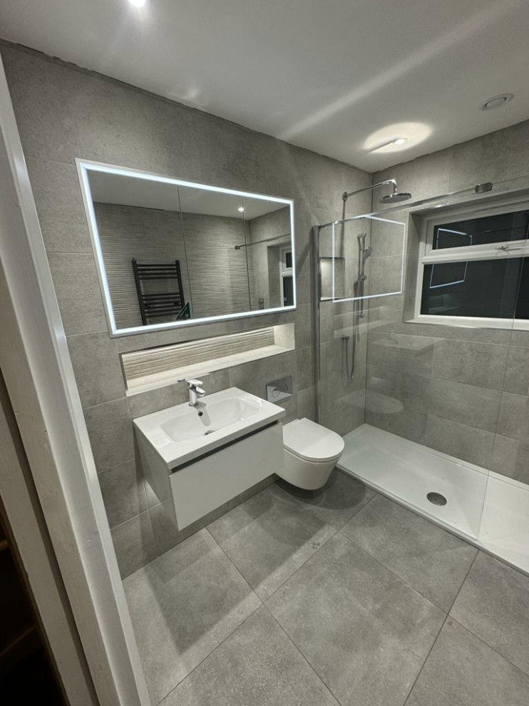 Design ideas for a medium sized contemporary bathroom in Surrey with white cabinets, an alcove shower, a wall mounted toilet, grey tiles, grey walls, grey floors, an open shower, a single sink and a floating vanity unit.
