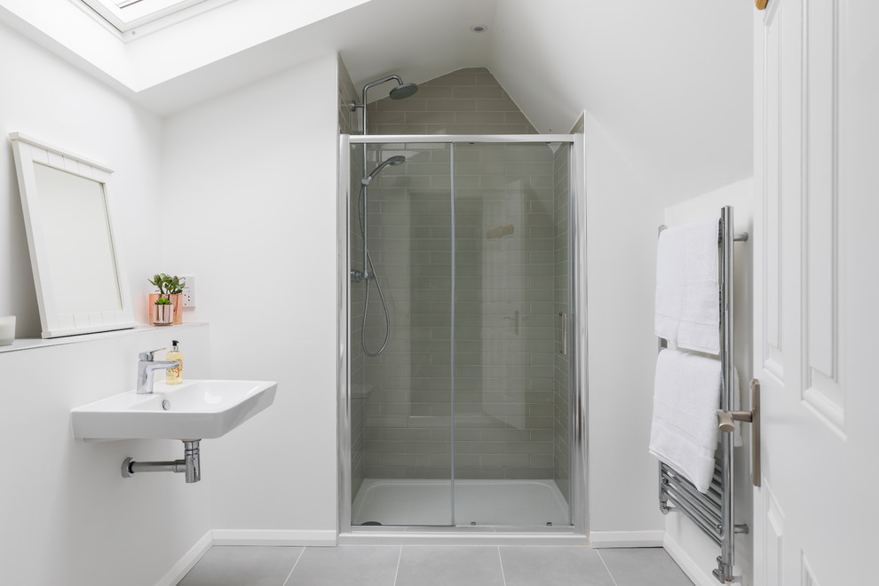 Inspiration for a mid-sized transitional master bathroom in Oxfordshire with a wall-mount toilet, gray tile, ceramic tile, white walls, ceramic floors, a wall-mount sink, grey floor and a sliding shower screen.