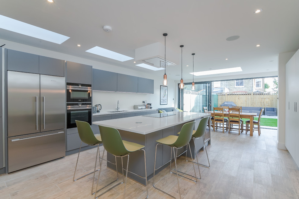 Photo of a mid-sized contemporary single-wall eat-in kitchen in London with an undermount sink, flat-panel cabinets, grey cabinets, quartzite benchtops, white splashback, stainless steel appliances, light hardwood floors, with island, brown floor and white benchtop.