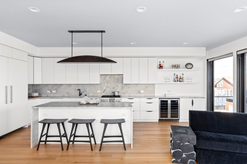 This is an example of a contemporary l-shaped open plan kitchen in New York with an undermount sink, flat-panel cabinets, white cabinets, grey splashback, vinyl floors, with island, brown floor, grey benchtop and panelled appliances.