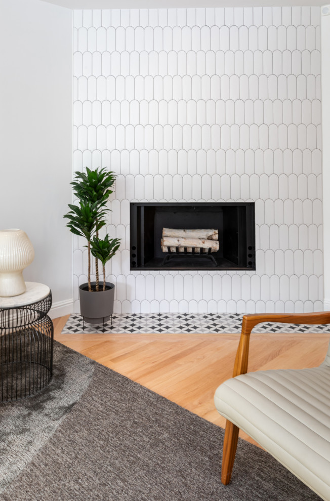 Cette photo montre un salon moderne de taille moyenne et ouvert avec un mur blanc, parquet clair, une cheminée ribbon, un manteau de cheminée en carrelage, un sol marron et un plafond décaissé.