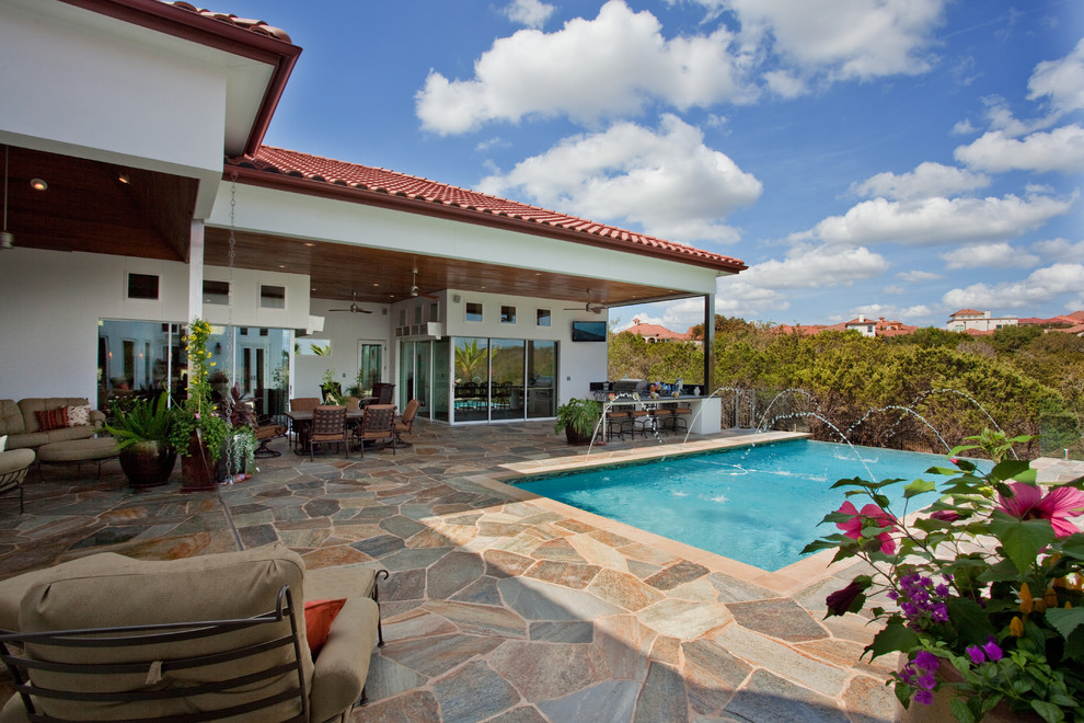 Mid-sized mountain style backyard stone and rectangular infinity pool photo in Austin