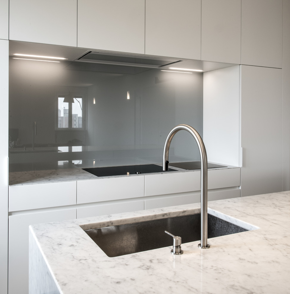 Esempio di un'ampia cucina minimalista con lavello sottopiano, ante lisce, ante bianche, top in marmo, paraspruzzi grigio, paraspruzzi con lastra di vetro e elettrodomestici in acciaio inossidabile