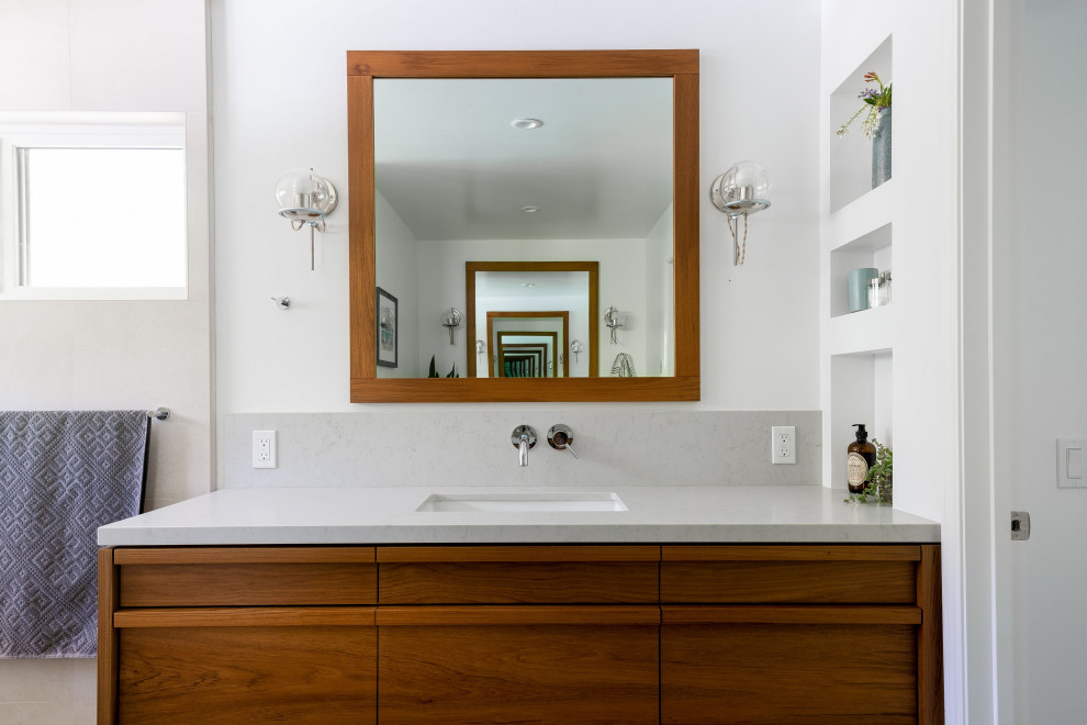 Large transitional master gray tile and ceramic tile ceramic tile and gray floor freestanding bathtub photo with furniture-like cabinets, brown cabinets, a two-piece toilet, white walls, a drop-in sink, quartz countertops and gray countertops